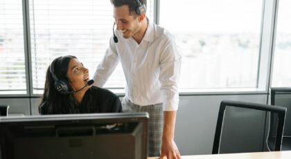 Smiling colleagues wearing headsets working together at a call center in a modern office setting.