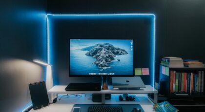 Stylish home office desk setup featuring LED lights, monitor, laptop, and essentials for a productive workspace.
