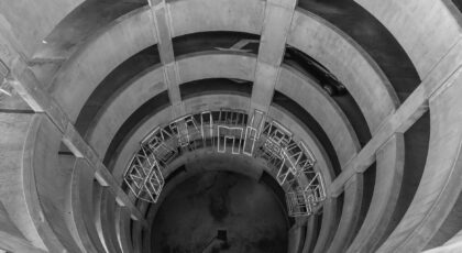 A grayscale view of a spiral concrete parking garage with geometric design elements.